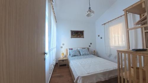 a white bedroom with a bed and a window at Ana Maria Boutique House in Samothraki
