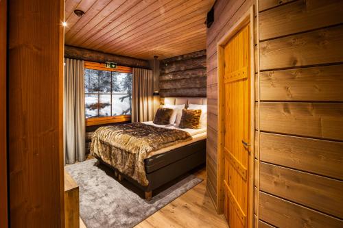 a bedroom in a log cabin with a bed and a window at Saariselkä Kelo Lodge in Saariselka