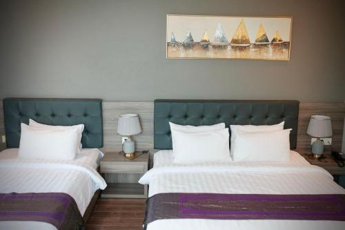 two beds in a hotel room with two lamps at KEP BAY HOTEL & RESORT in Kep