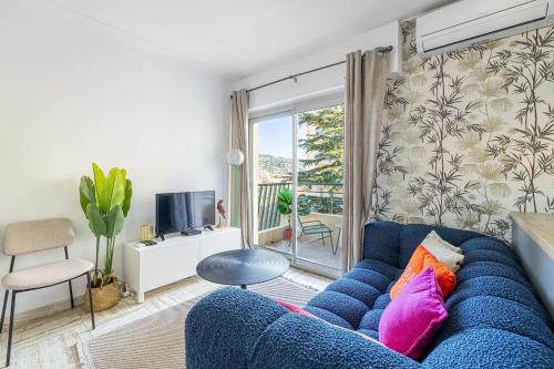 - un canapé bleu dans le salon doté d'une fenêtre dans l'établissement LA PALMERAIE joyeux studio avec balcon, à deux pas de la Banane, à Cannes