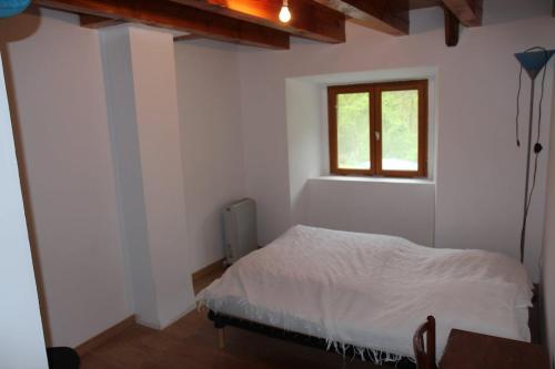 une chambre avec un lit blanc et une fenêtre dans l'établissement Maison de campagne en Ardèche, à Arcens