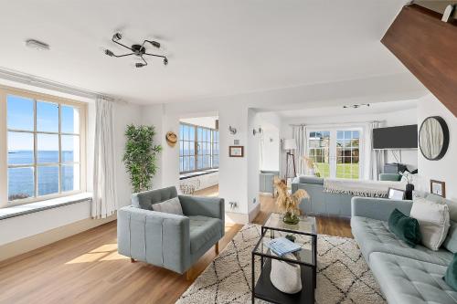 a living room with a couch and chairs and windows at NEW 2024 Modern Luxury Holiday Home on the Beach in Devon - Free Parking, Pets Welcome, Sleeps 10 in Plymouth