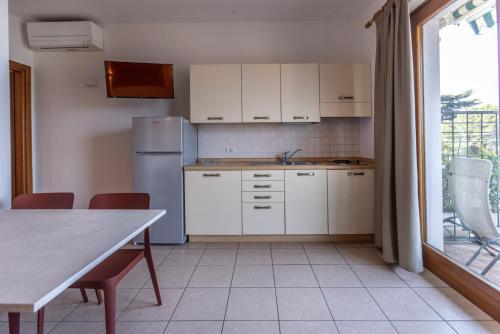 a kitchen with a refrigerator and a table with chairs at Residence Solei Classic & Plus in Brenzone sul Garda