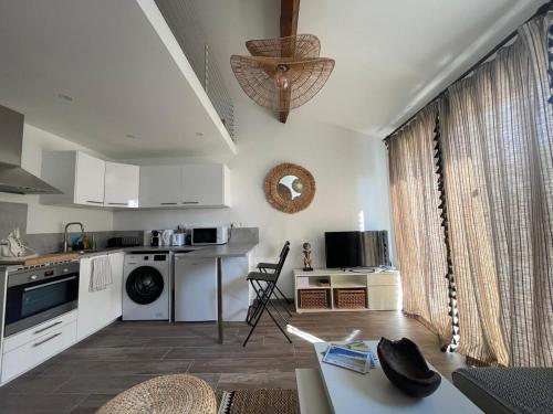 une cuisine avec des armoires blanches et une laveuse et une sécheuse dans l'établissement L'écrin des Pins, à Sausset-les-Pins