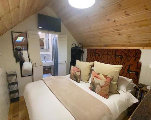 a bedroom with a large white bed with pillows at Woodmans Huts in Haverthwaite
