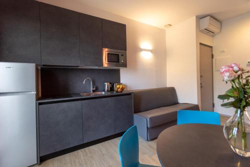 a kitchen with a refrigerator and a couch and a table at Residence Solei Classic & Plus in Brenzone sul Garda