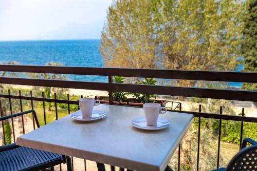 a table with two cups on a balcony with the ocean at Residence Solei Classic & Plus in Brenzone sul Garda