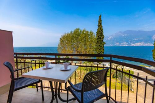 a table and chairs on a balcony with a view of the ocean at Residence Solei Classic & Plus in Brenzone sul Garda