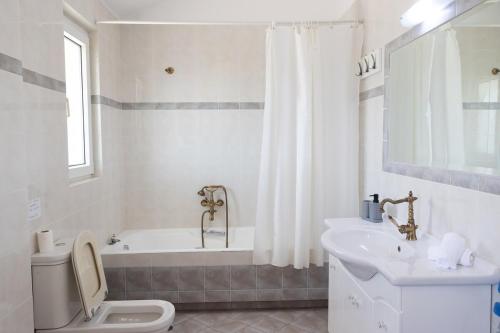 a bathroom with a tub and a toilet and a sink at Aethra Villa in Sounio