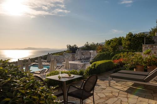 a patio with a table and chairs next to the water at Karavia Lux Inn in Afissos