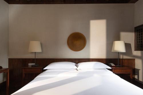 a bedroom with a large white bed with two lamps at Lijiang Old Town Lanshe hotel in Lijiang