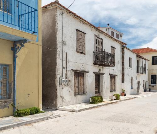 an old white building with windows and a balcony at Karavia Lux Inn in Afissos