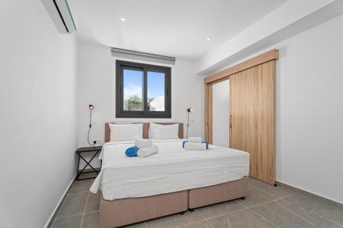 a bedroom with a bed with white sheets and a window at PANATHEON - Luxury 1 & 2 bdr bungalows 300 meters from sandy beach! in Ayia Napa