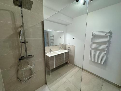 une salle de bain avec une douche en verre et un lavabo dans l'établissement Appartement 225, CORAL à la plage de la Conque, au Cap d'Agde