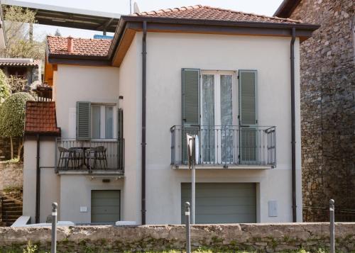 a white house with green shutters and a balcony at CHARMING MOMENT di Villa Porta - Jolie Maison in Luino