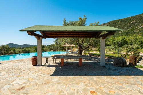 a pavilion with a picnic table next to a pool at Harmònia Residence in Villasimius