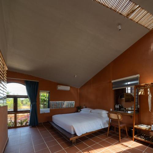 a bedroom with a bed and a desk and a window at Chuồn Chuồn Retreat in Phan Thiet