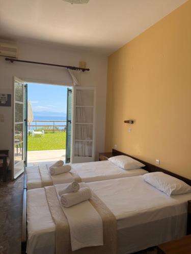two beds in a room with a view of the ocean at Nikoli Apartments in Benitses