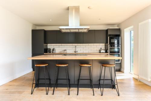 a kitchen with black cabinets and a counter with stools at Iona – Bracklesham Bay in Chichester