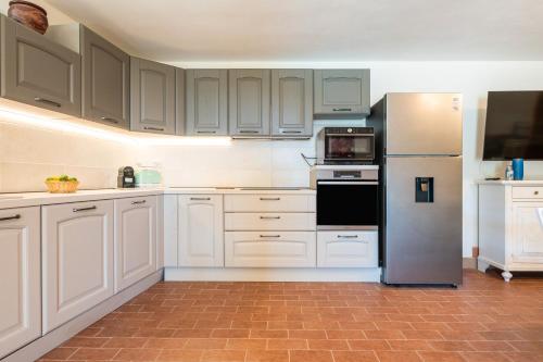 a kitchen with white cabinets and a stainless steel refrigerator at Harmònia Residence in Villasimius