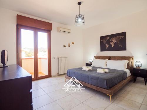 una camera da letto con un letto, una televisione e un balcone di Casa Maura - MORADA a Iglesias