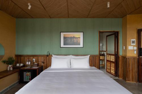 a bedroom with a large bed and a green wall at Chuồn Chuồn Retreat in Phan Thiet