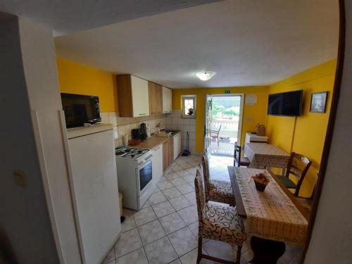 a kitchen with yellow walls and a table with chairs at Apartments Kampor (4235) in Kampor