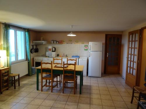 une cuisine avec une table, des chaises et un réfrigérateur dans l'établissement L'Azeuil, à Saint-Vidal