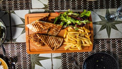 a plate of food with fries and salad on a table at Hotel Philosophy in Amman