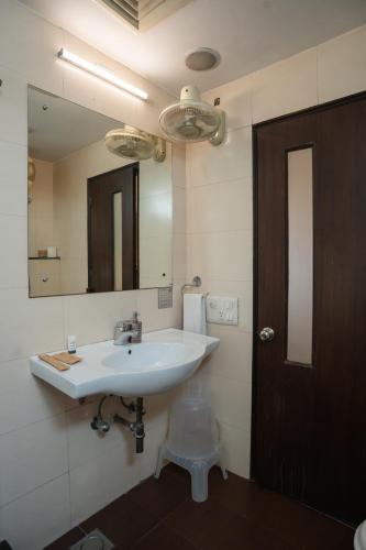 a bathroom with a white sink and a mirror at Ahuja Residency Cyber City II in Gurgaon