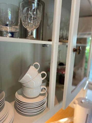 a shelf with plates and a tea pot and glasses at Cart Shed Heaven in Sissinghurst