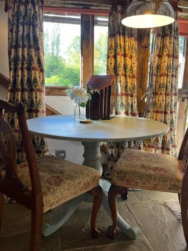 a table with a vase of flowers and two chairs at Cart Shed Heaven in Sissinghurst
