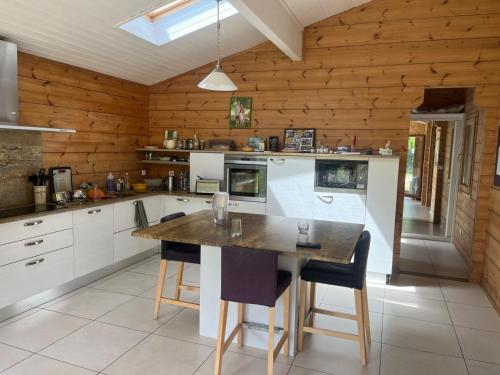 une cuisine avec une table et des chaises dans l'établissement Villa de charme en bois avec Piscine privée calme et proche de Toulouse, à Pibrac