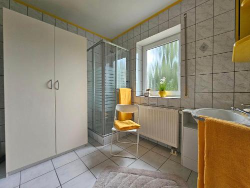 a bathroom with a tub and a sink and a chair at Ferienwohnung Köhler Heymann in Dornholzhausen