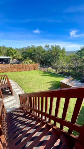 a wooden bench sitting on a patio with a yard at The Wooden House in Plettenberg Bay