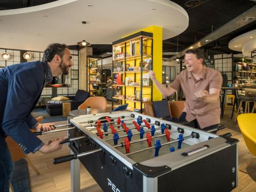 two men playing with a large foosball table at Campanile Hotel & Restaurant Amsterdam Zuid-Oost in Amsterdam