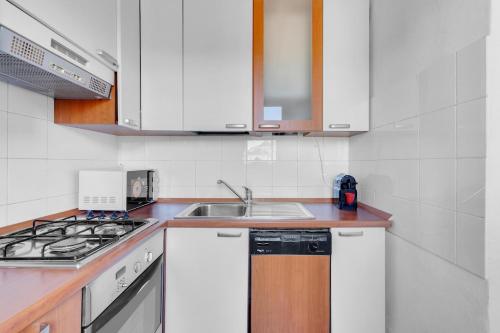 una cucina con mobili bianchi e un lavandino di Metro M2 e AC - Open Space moderno a Milano a Milano