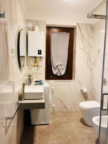 a bathroom with a sink and a toilet and a window at Torre Sances Holiday Apartament in Birgi Vecchi