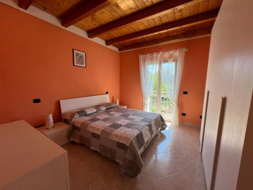 a bedroom with orange walls and a bed and a window at Penthouse Valentino in Intra
