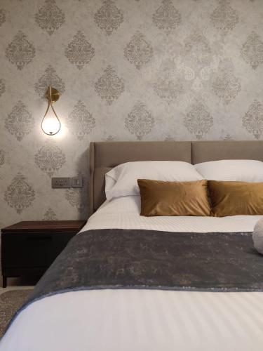 a bedroom with a bed with white sheets and gold pillows at Luxury Seaside Eastlynn Flat Ghadira, Mellieha in Mellieħa