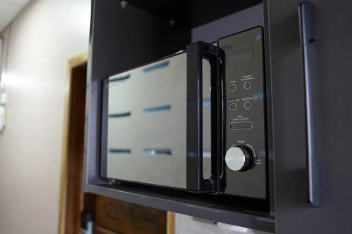a black microwave oven on a wall at The Hideaway in Accra