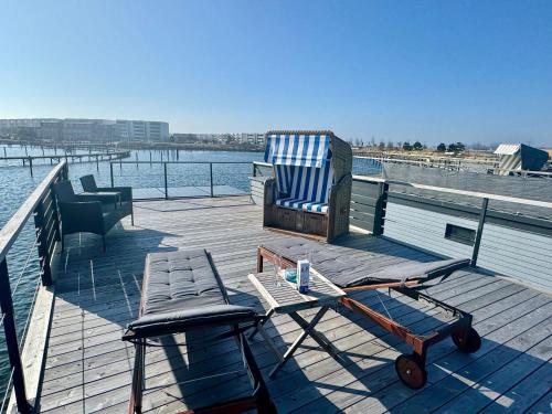 a deck with a chair and a bench on the water at Hausboot Lilla Lina in Fehmarn