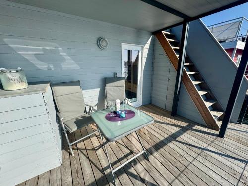 a patio with a table and chairs on a deck at Hausboot Lilla Lina in Fehmarn