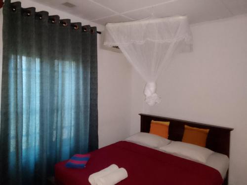 a bedroom with a red bed and a window with curtains at Sky Villa Sigiriya in Sigiriya