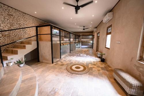 a large room with a ceiling fan and stairs at Penida Patio Hostel in Toyapakeh
