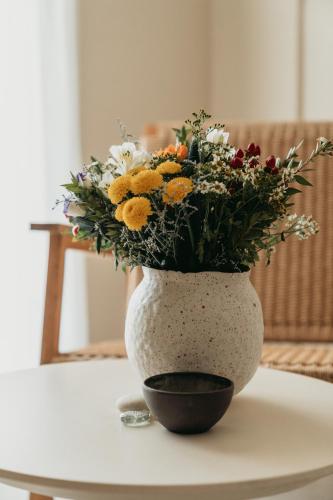 a white vase with a bouquet of flowers on a table at Athera Suites Mykonos in Tagou
