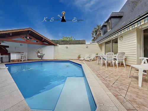 a swimming pool in a yard with chairs and a table at L Oasis tout confort en Béarn in Gelos