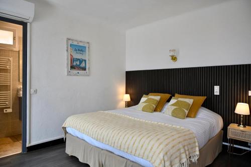 a bedroom with a large bed with yellow pillows at Hôtel La Petite Bohème in Le Lavandou