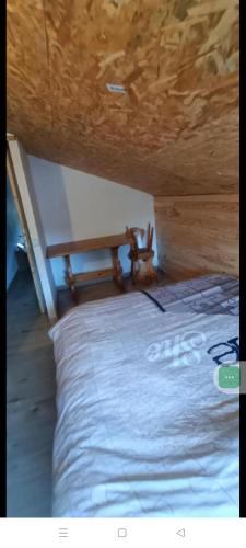a bed in a room with a wooden ceiling at Chalet 5 personnes avec piscine in Yvoir