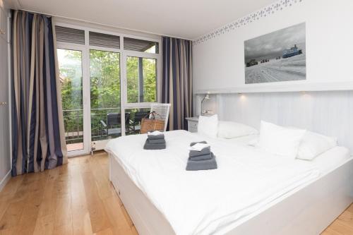 a bedroom with a large white bed and a large window at Wohnung 14 Am Januspark in Juist